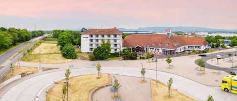 A hotel with a central courtyard, a parking area, and a view of the surrounding landscape.