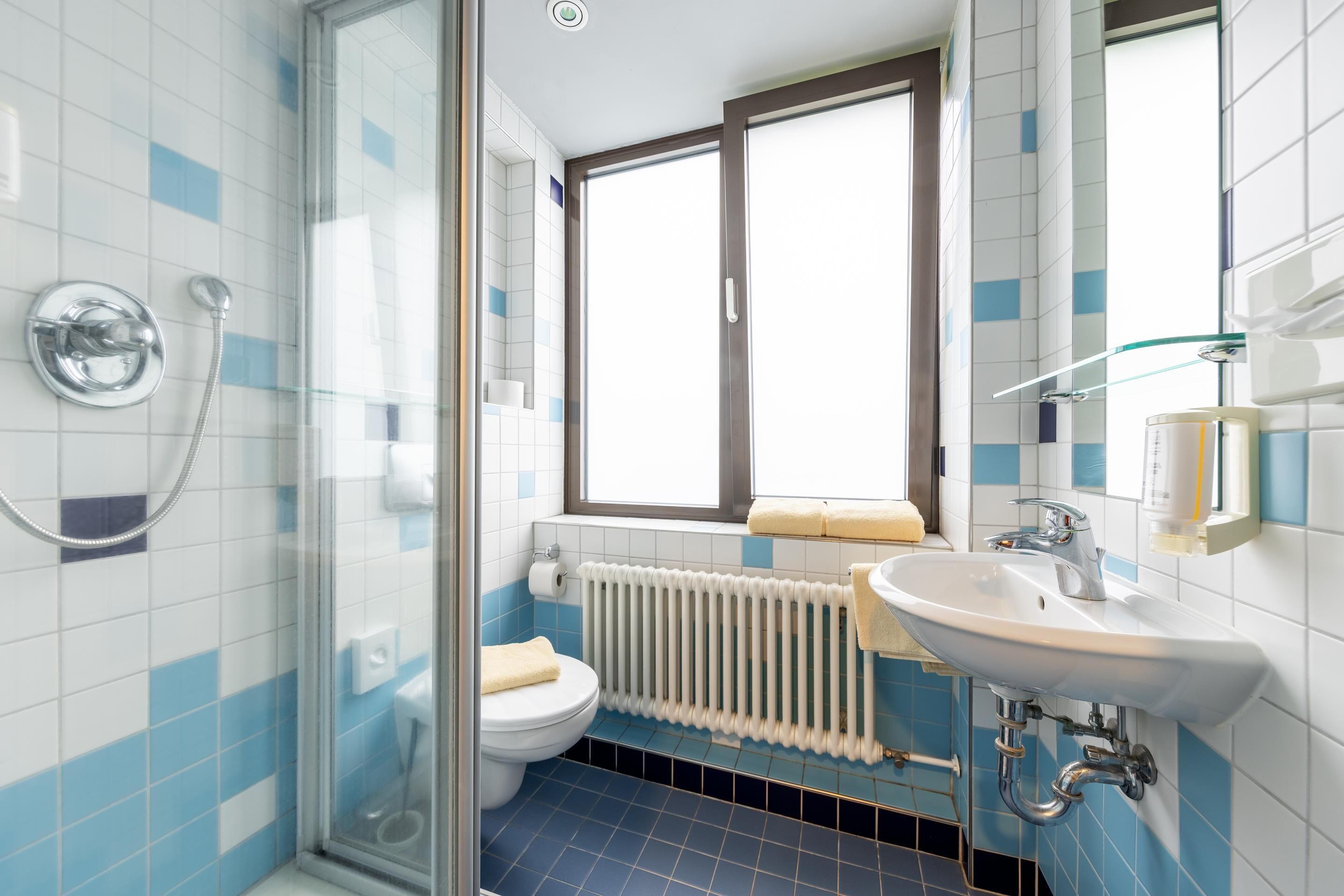 A bathroom with a glass shower enclosure, a white sink, and a toilet.