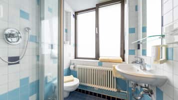 A bathroom with a glass shower enclosure, a white sink, and a toilet.