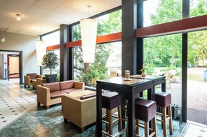 A lobby with wicker furniture, a bar area, and large windows offering a view of the outdoors.