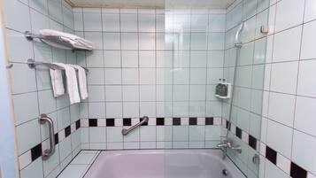 A bathroom with a bathtub, grab bars, and a towel rack.