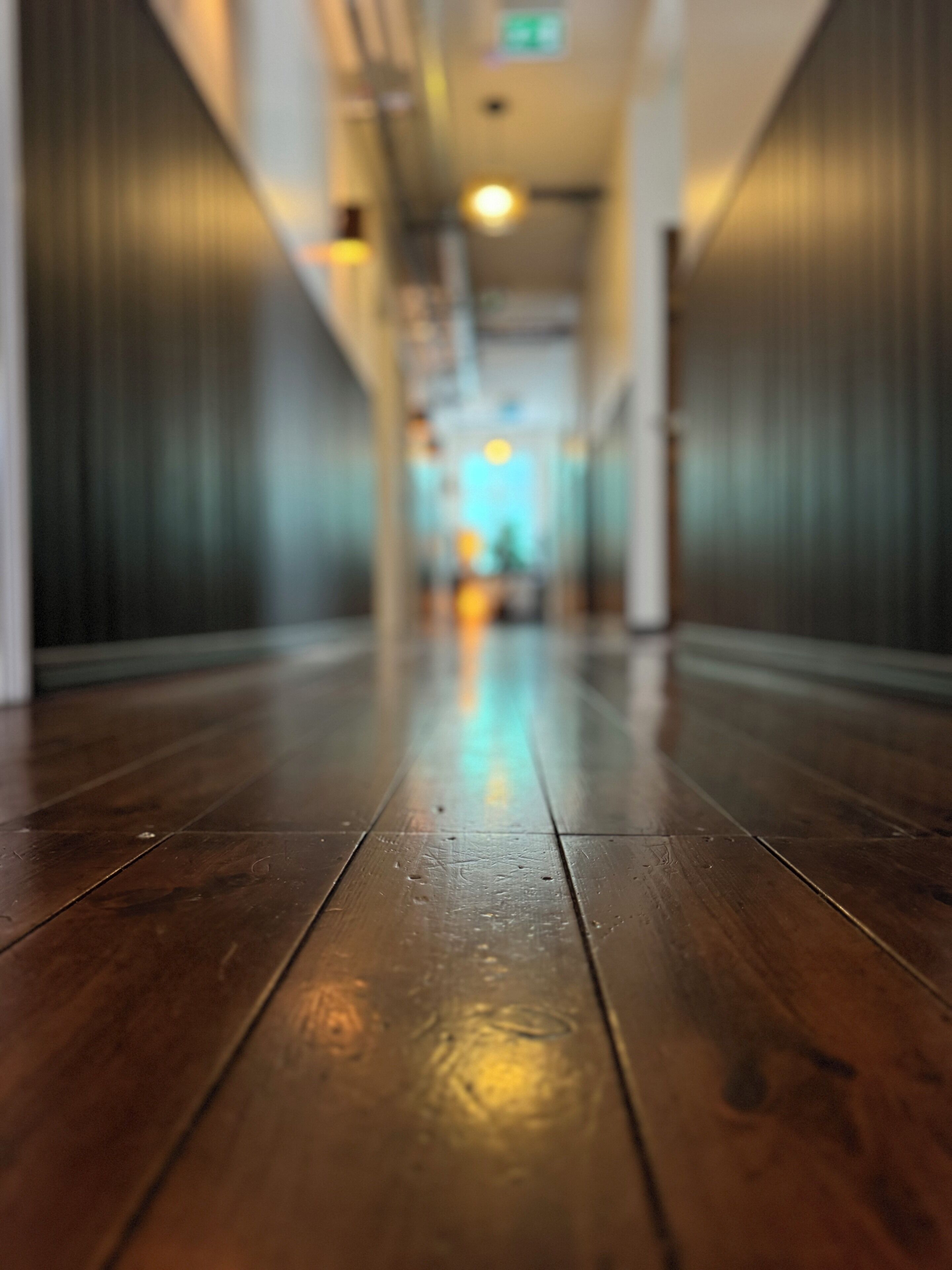 A wooden floor in a hallway with a blurred background.