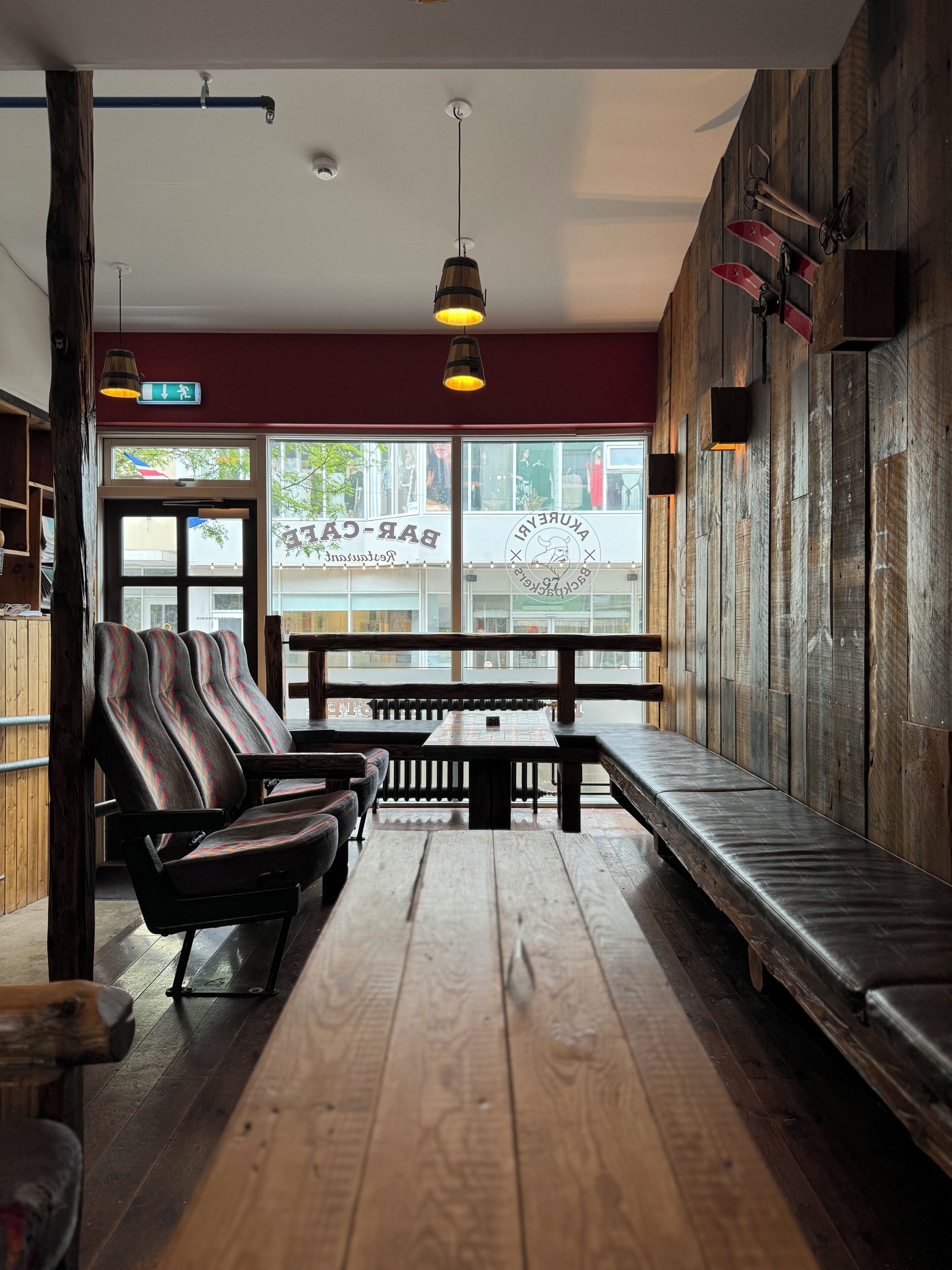 Interior de restaurante con suelo de madera, bancos y mesas.