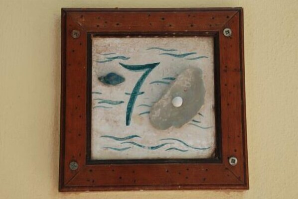 A framed number 7 with a circular object and waves, mounted on a wall. - Agriturismo Terrauzza sul Mare (Syracuse)