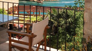 Un balcon avec vue sur la mer, une chaise en bois et une table.