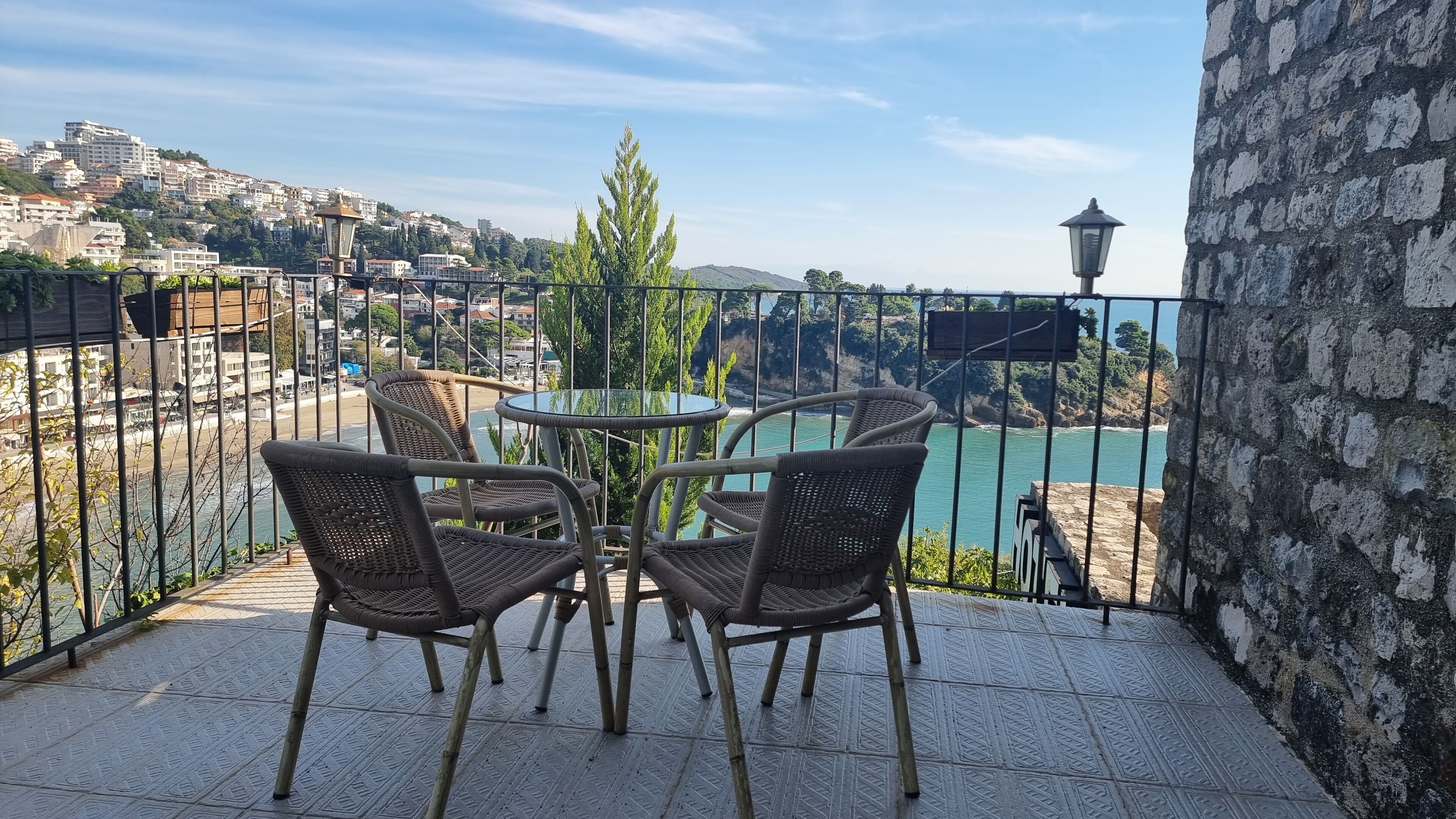 Una terrazza con sedie in vimini e un tavolo di vetro, vista su un fiume e sullo skyline della città.