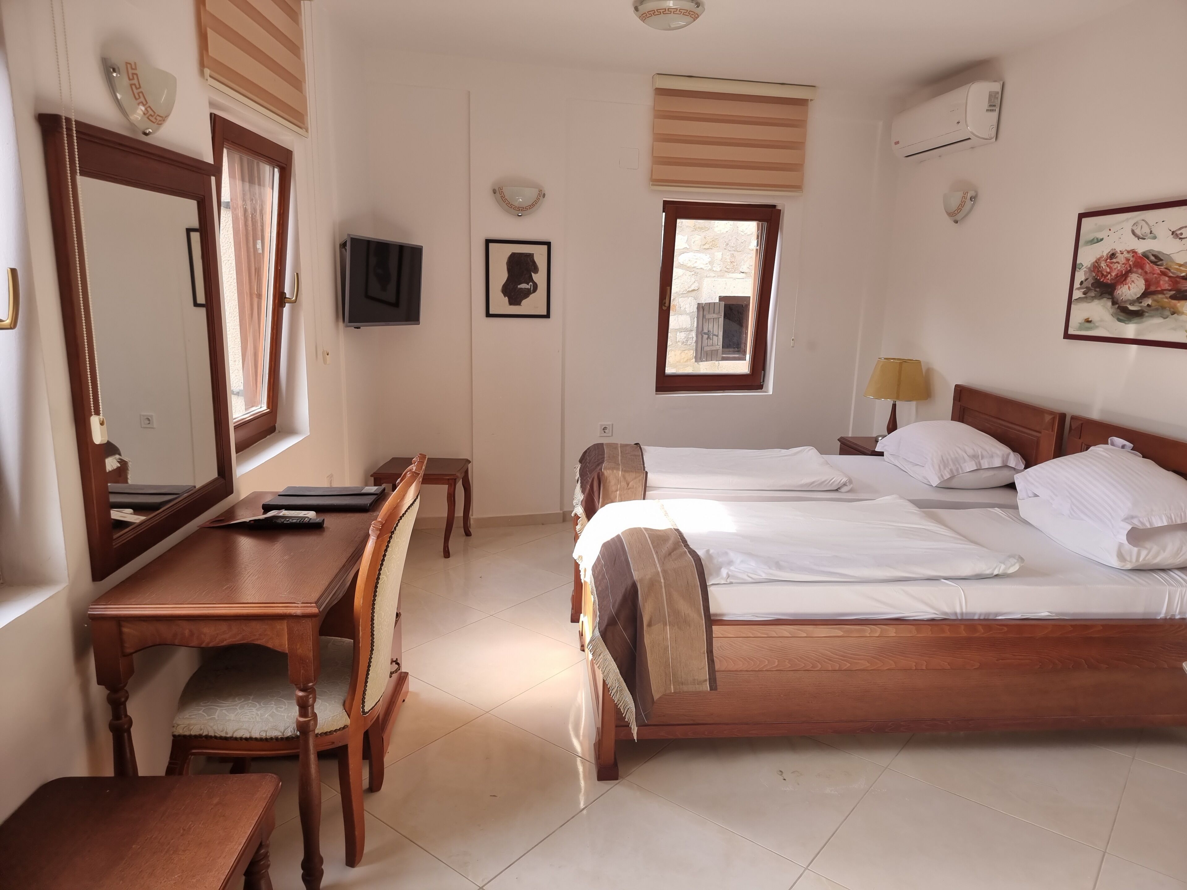 Habitación de hotel con cama de madera, un escritorio con silla, televisor y ventana con vista al exterior.