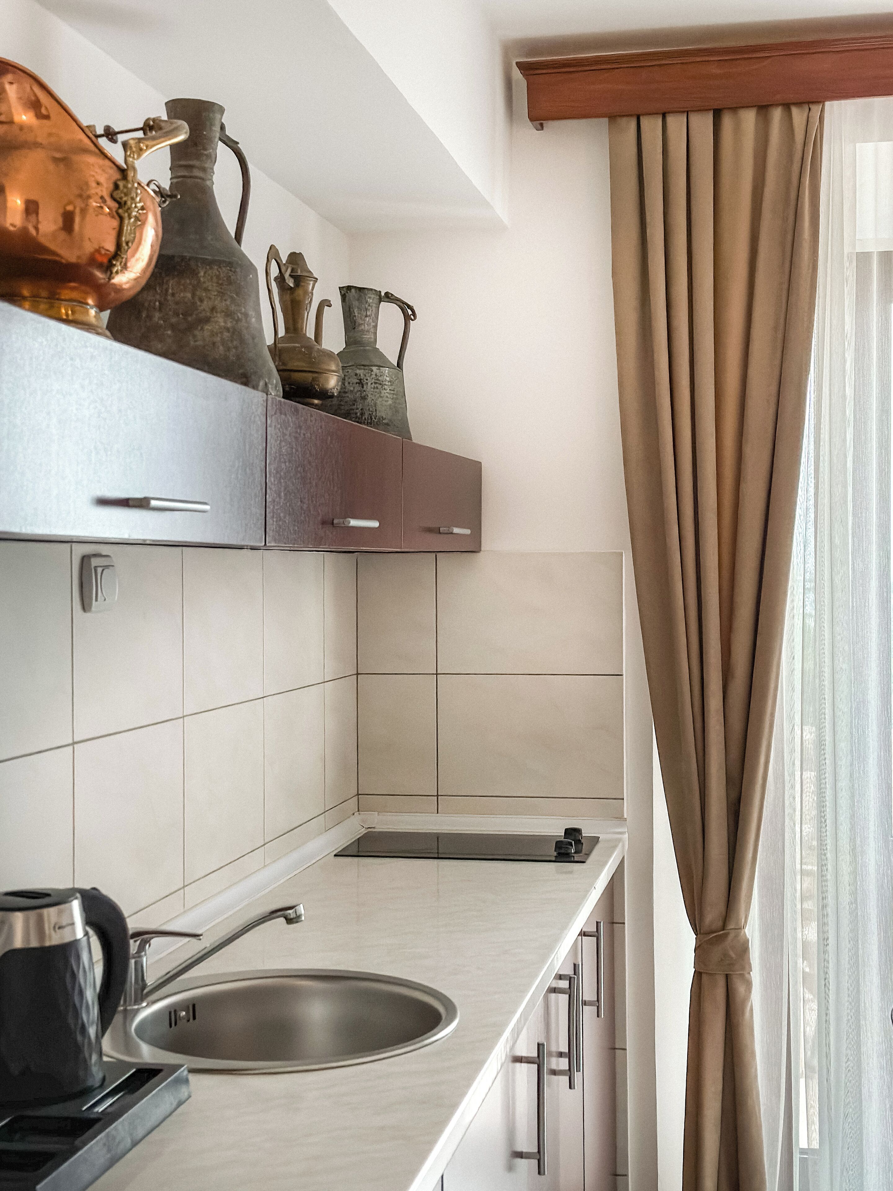 Una cocina moderna con un lavamanos integrado, estufa y repisa con objetos decorativos de metal.
