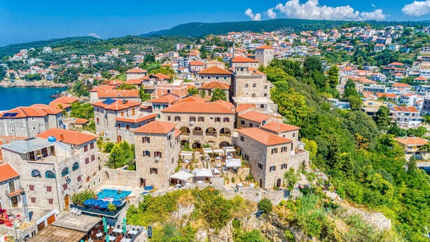 A coastal town with stone buildings, a central courtyard with outdoor seating, and a view of the sea. - Palata Venezia (Ulcinj)