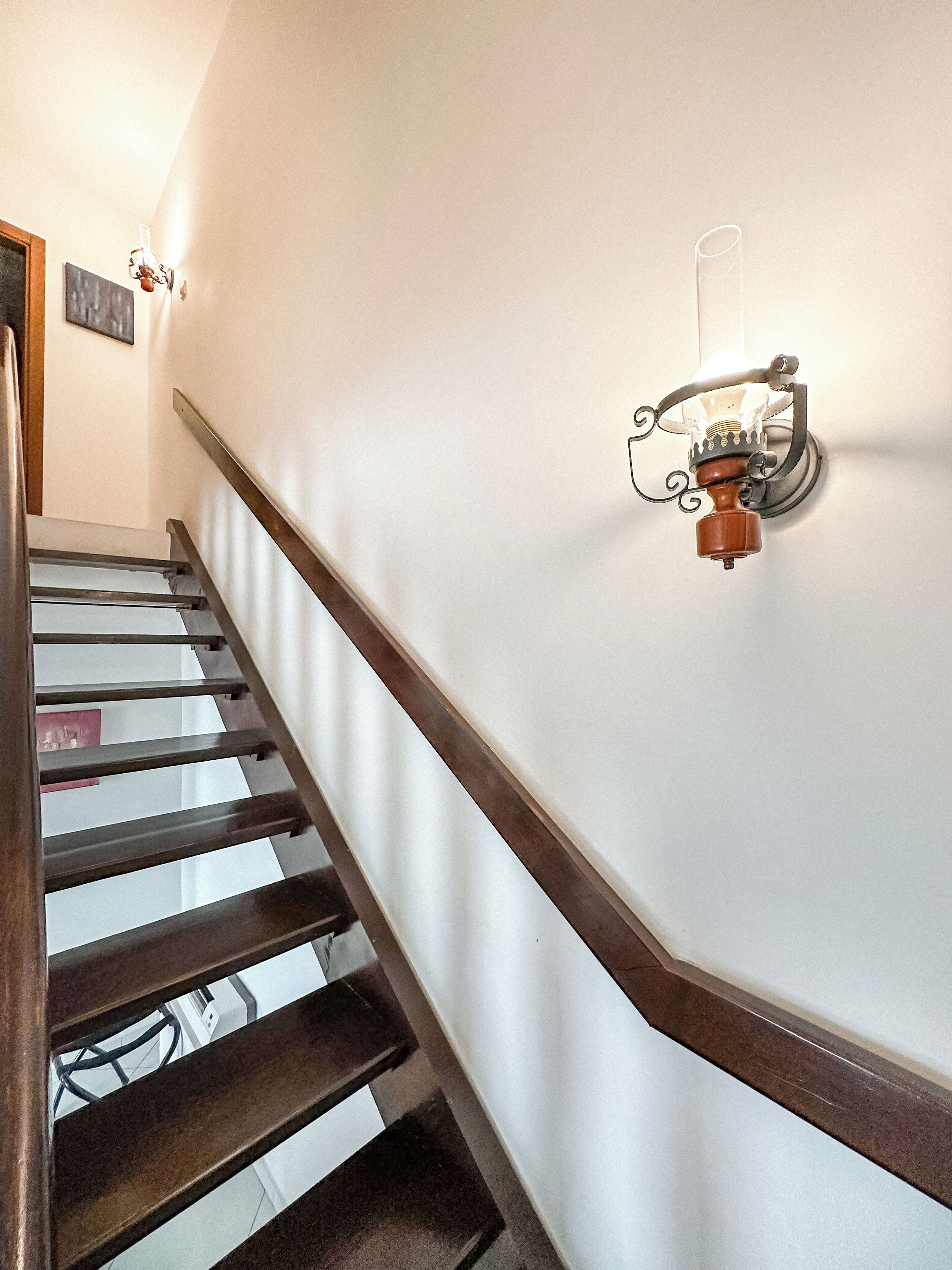 A staircase with wooden handrails and a wall-mounted light fixture.