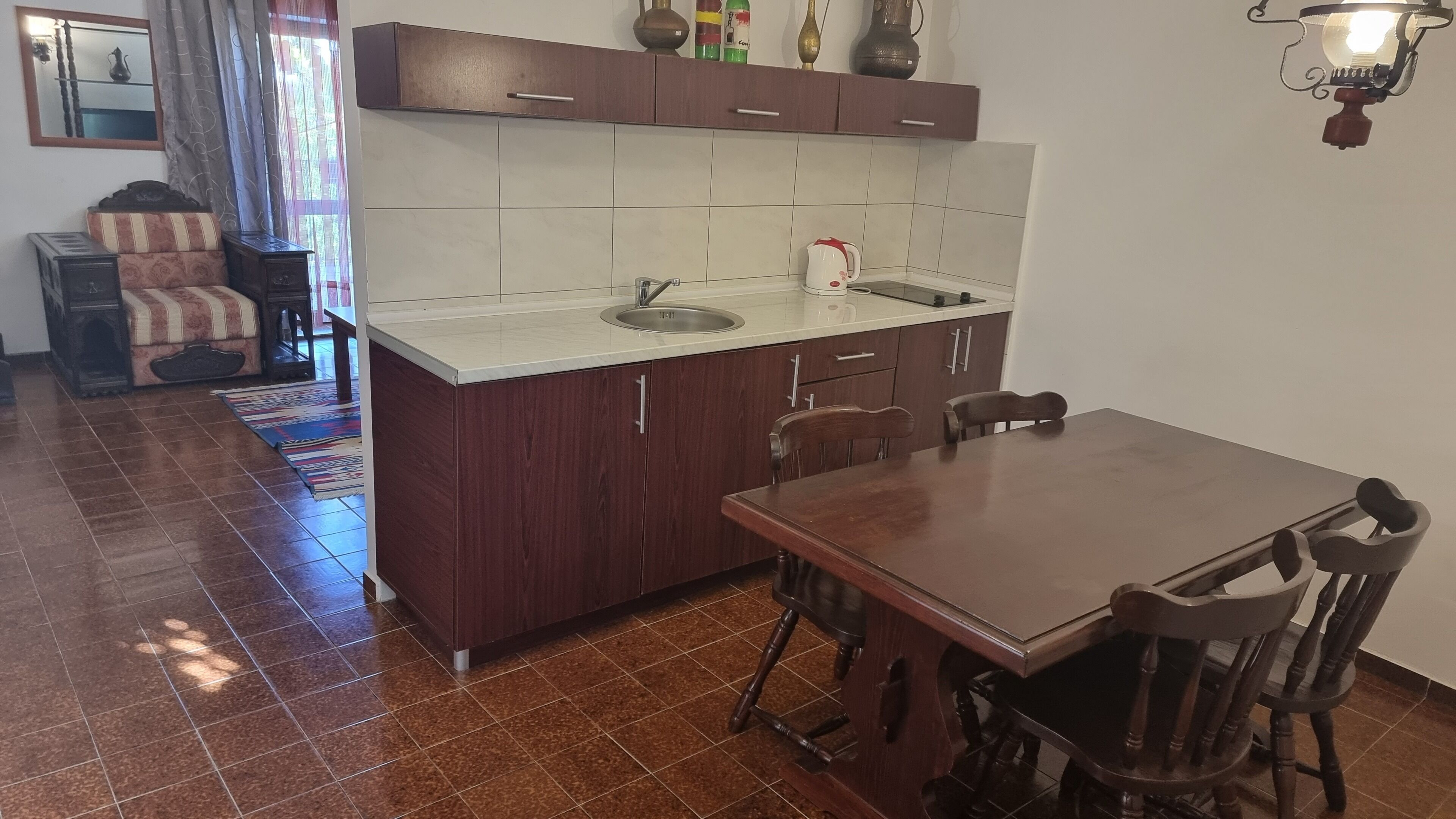 A compact kitchen with a sink, cabinets, and a dining area with chairs.