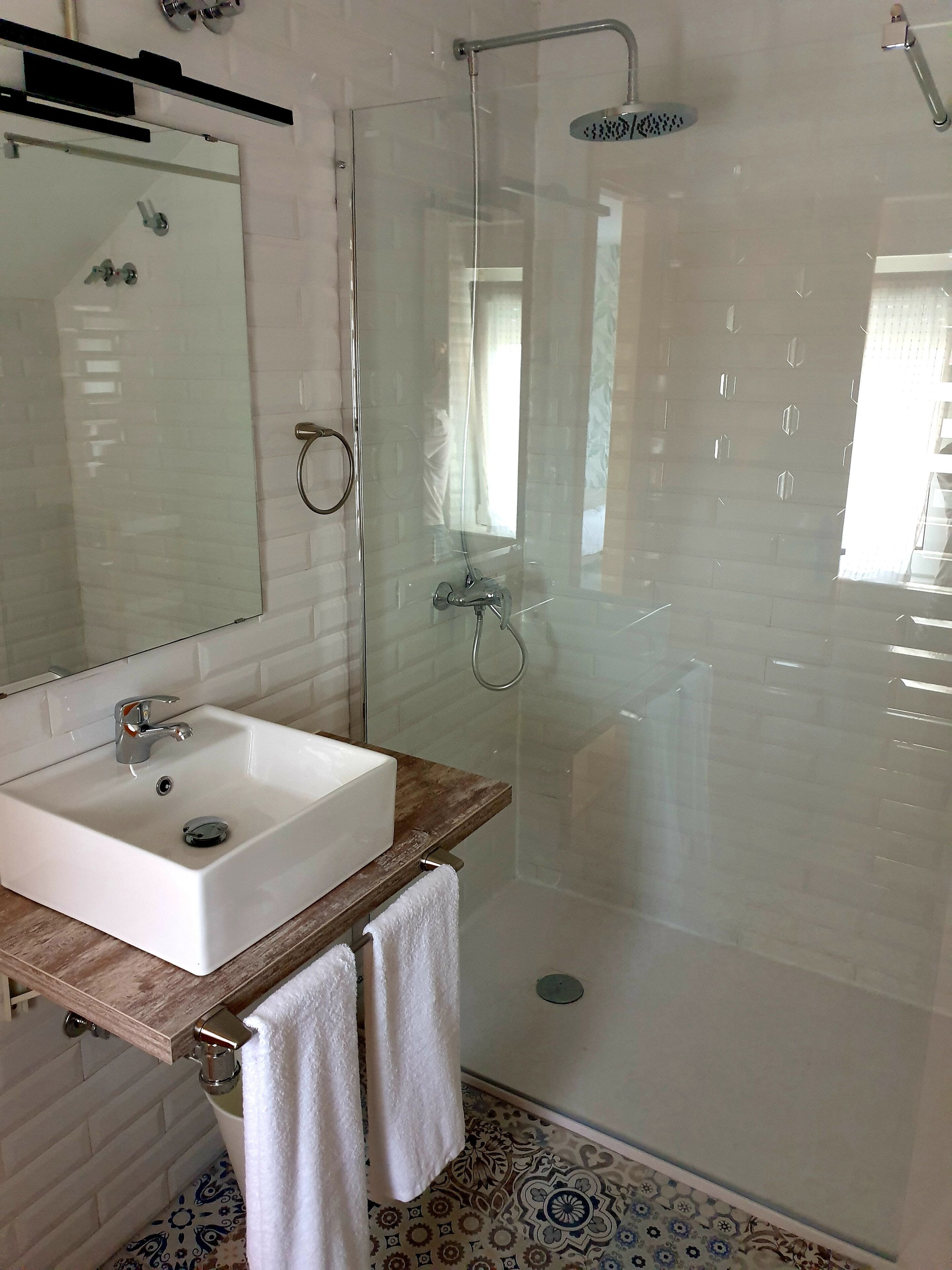 Un baño moderno con ducha envuelta en vidrio, un lavabo blanco y encimera de madera.
