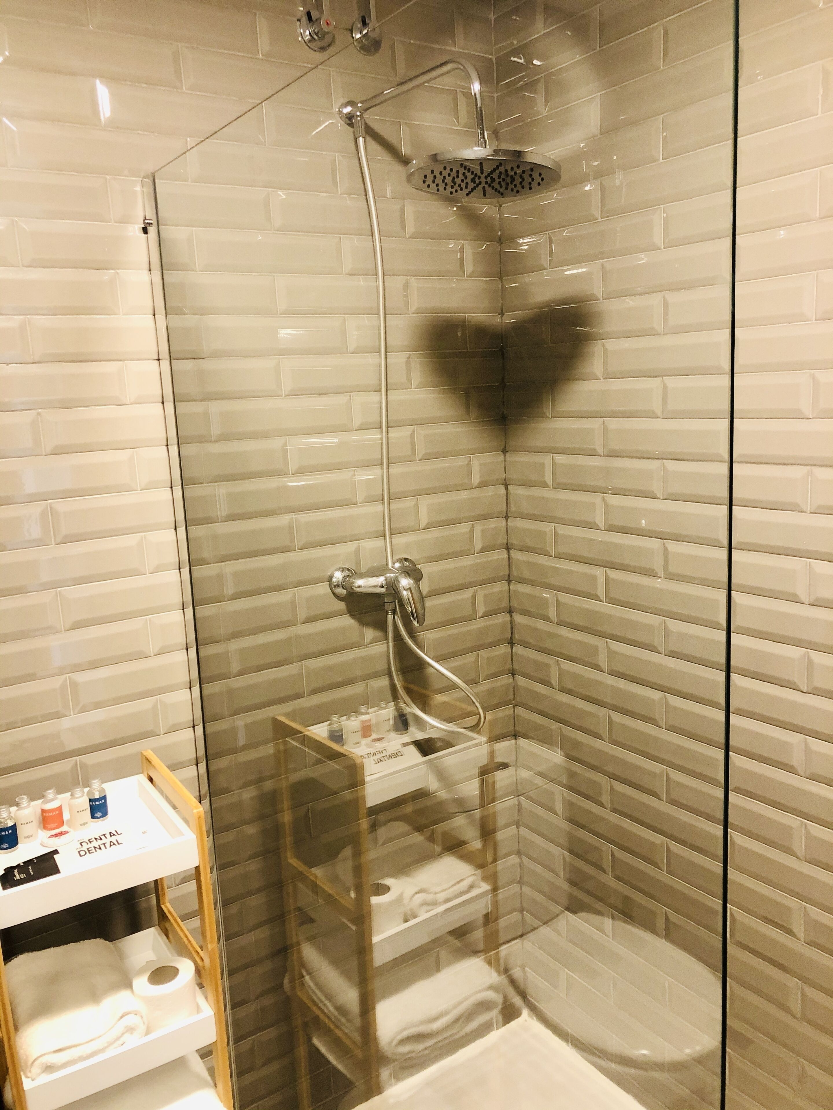 A glass-enclosed shower with a handheld showerhead and a wall-mounted faucet.