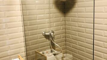 Ducha con cerramiento de vidrio, cabezal de ducha de mano y grifo empotrado.