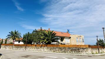 Un hotel costaner amb teulades vermelles, parets de pedra i palmeres.