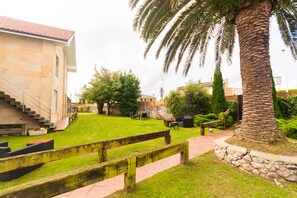 A courtyard with a stone building, palm trees, and outdoor seating. - Hotel Finca Alcamino (Santa Cruz de Bezana)
