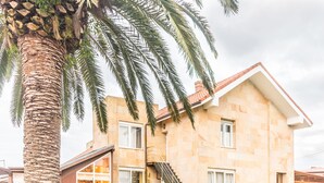 A two-story house with a stone facade, large windows, and a staircase leading to the upper floor. - Hotel Finca Alcamino (Santa Cruz de Bezana)
