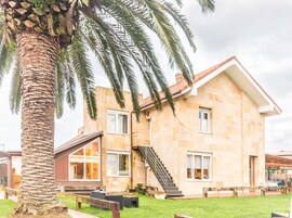 Una casa de dos pisos con fachada de piedra, ventanas amplias y una escalera que lleva al piso superior.