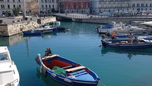 A harbor with boats docked, a bridge, and buildings in the background. - Casa Cristina (Syracuse)