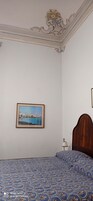 Un dormitorio con una cama, un cuadro en la pared y una mesita de noche con una lámpara.