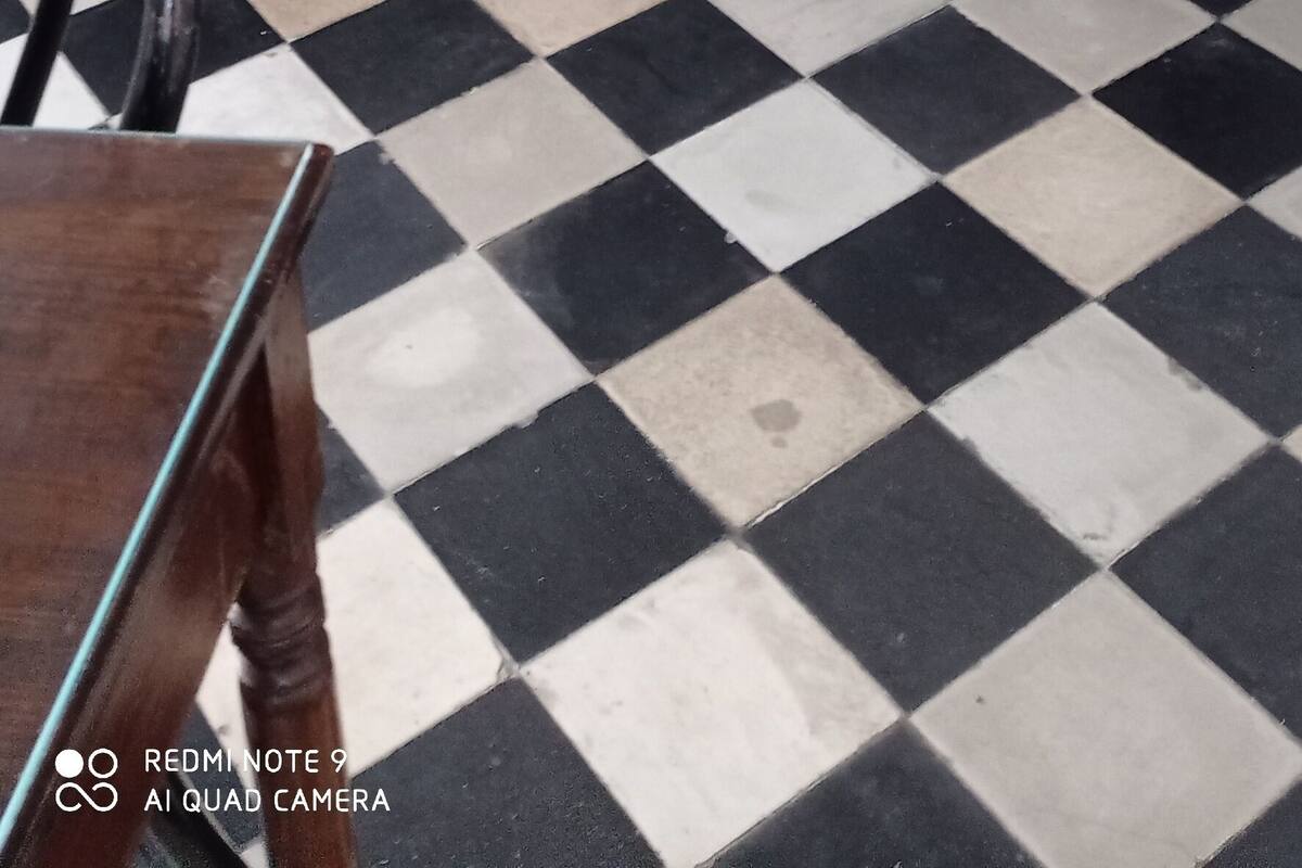 Un dormitorio con piso a cuadros, estructura de cama de madera y edredón estampado.