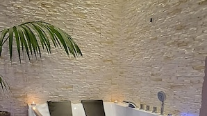 Et spa-område med en stenvæg, en massagestol og en lille plante.