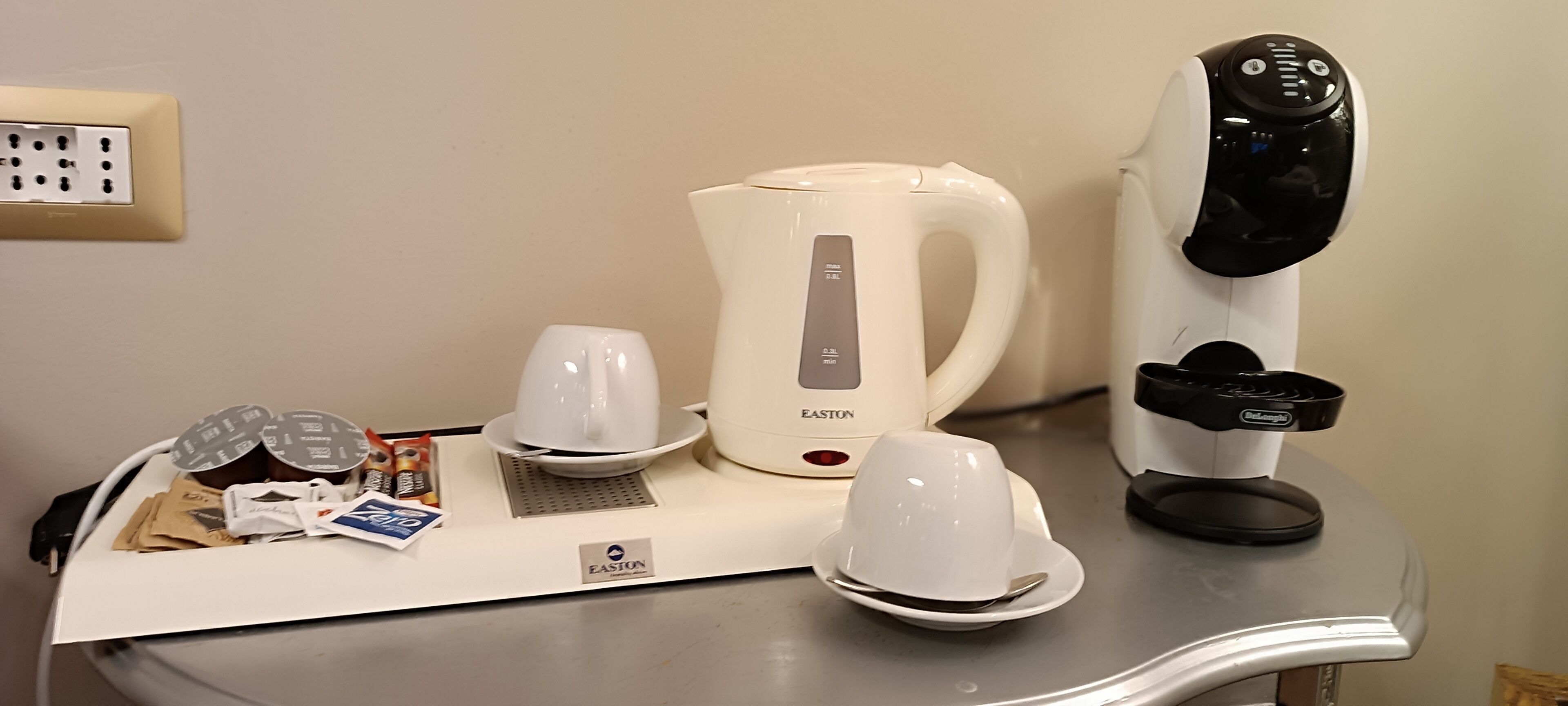 A kitchenette with a coffee maker, kettle, and electric kettle on a countertop.