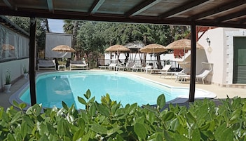 Una piscina al aire libre, sombrillas, sillones reclinables de piscina