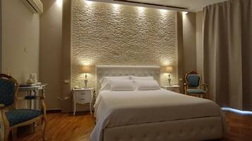 Una camera d'albergo con un letto grande, due comodini, una lampada, una sedia e un muro decorato.