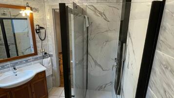 Ein modernes Badezimmer mit einer gläsernen Duschkabine, einem Waschtisch und einem Spiegel.