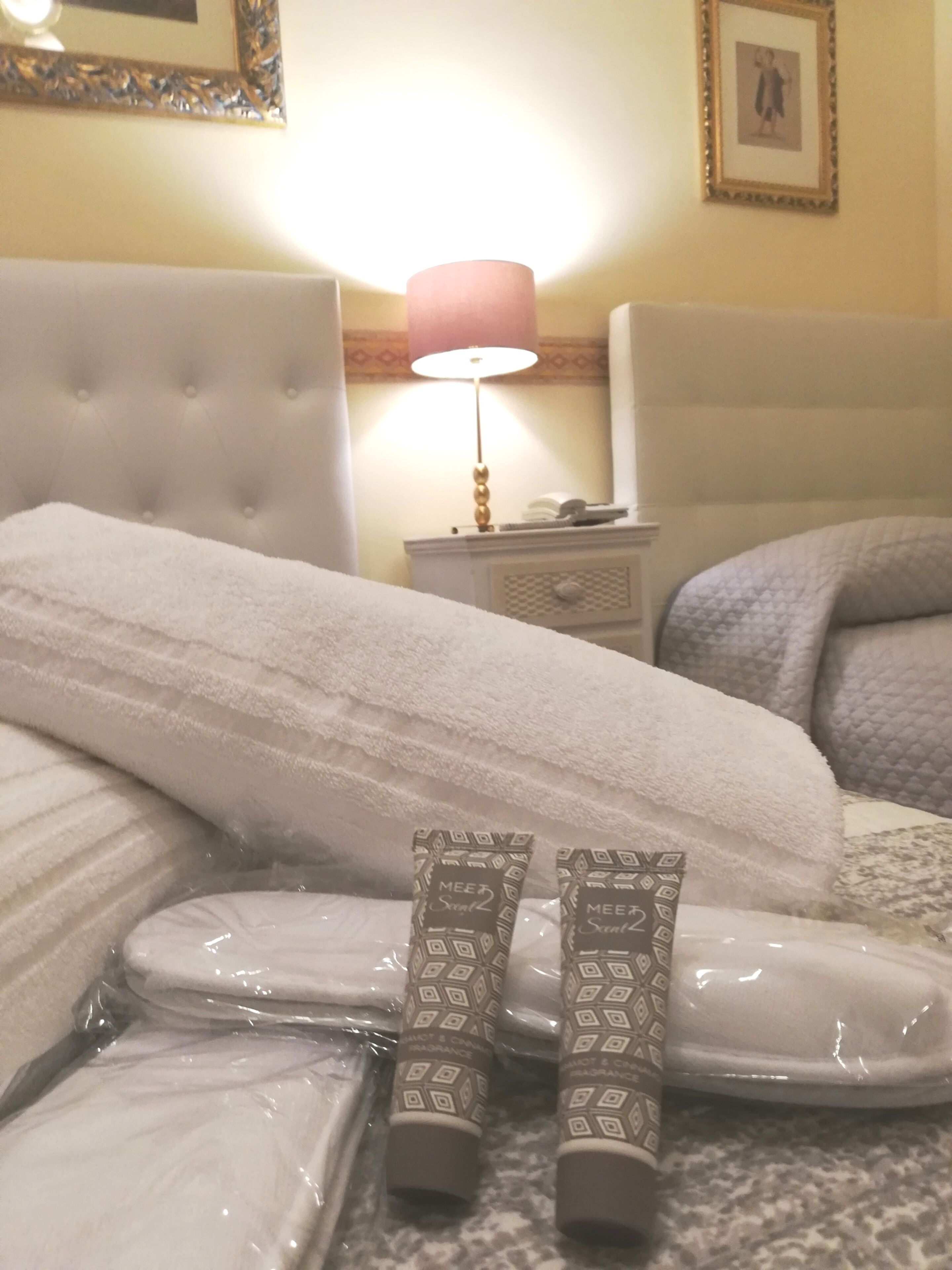 Un letto rifatto con un copriletto bianco e due beauty case sopra.