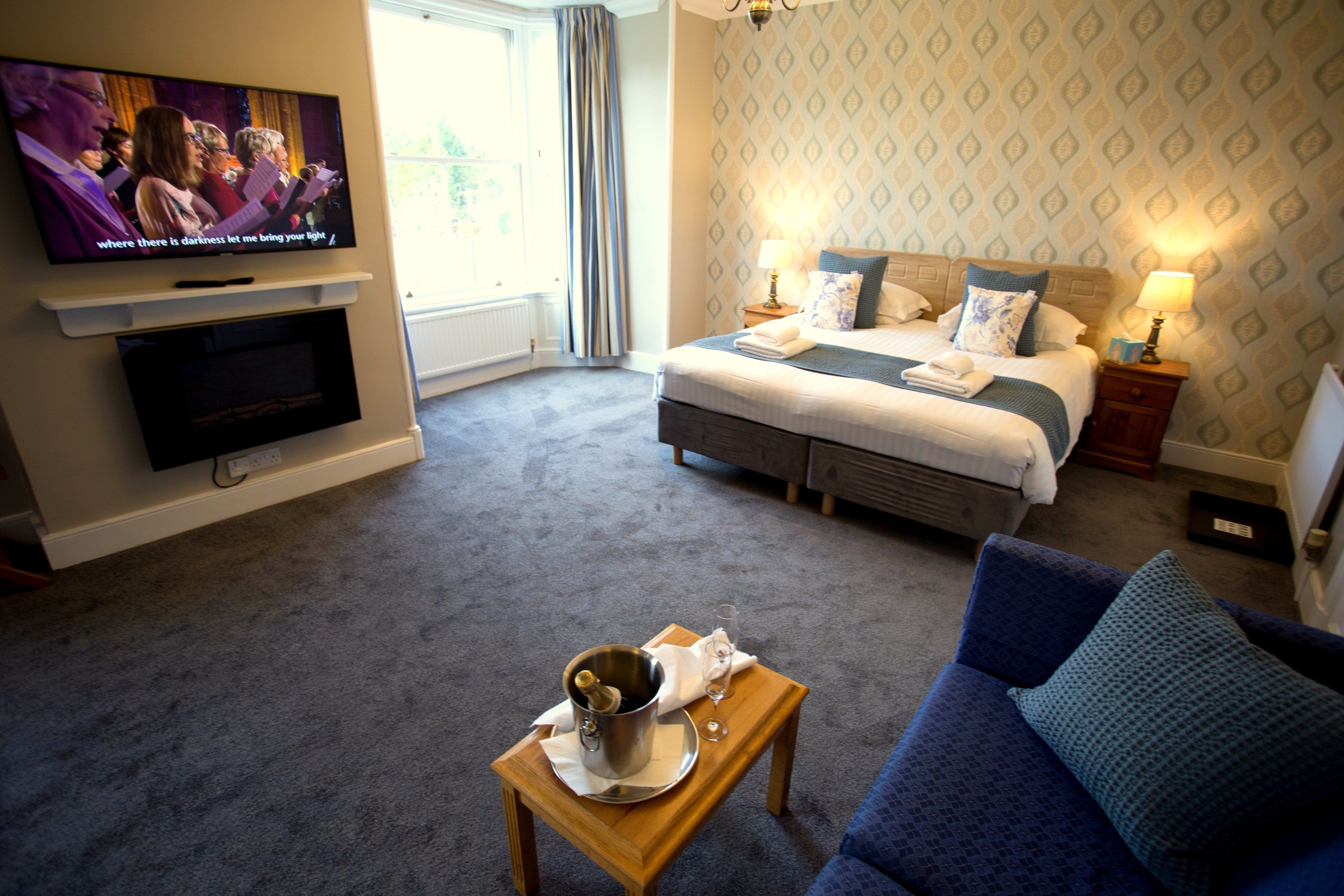 A hotel room with a bed, a TV, a coffee table, and a couch.