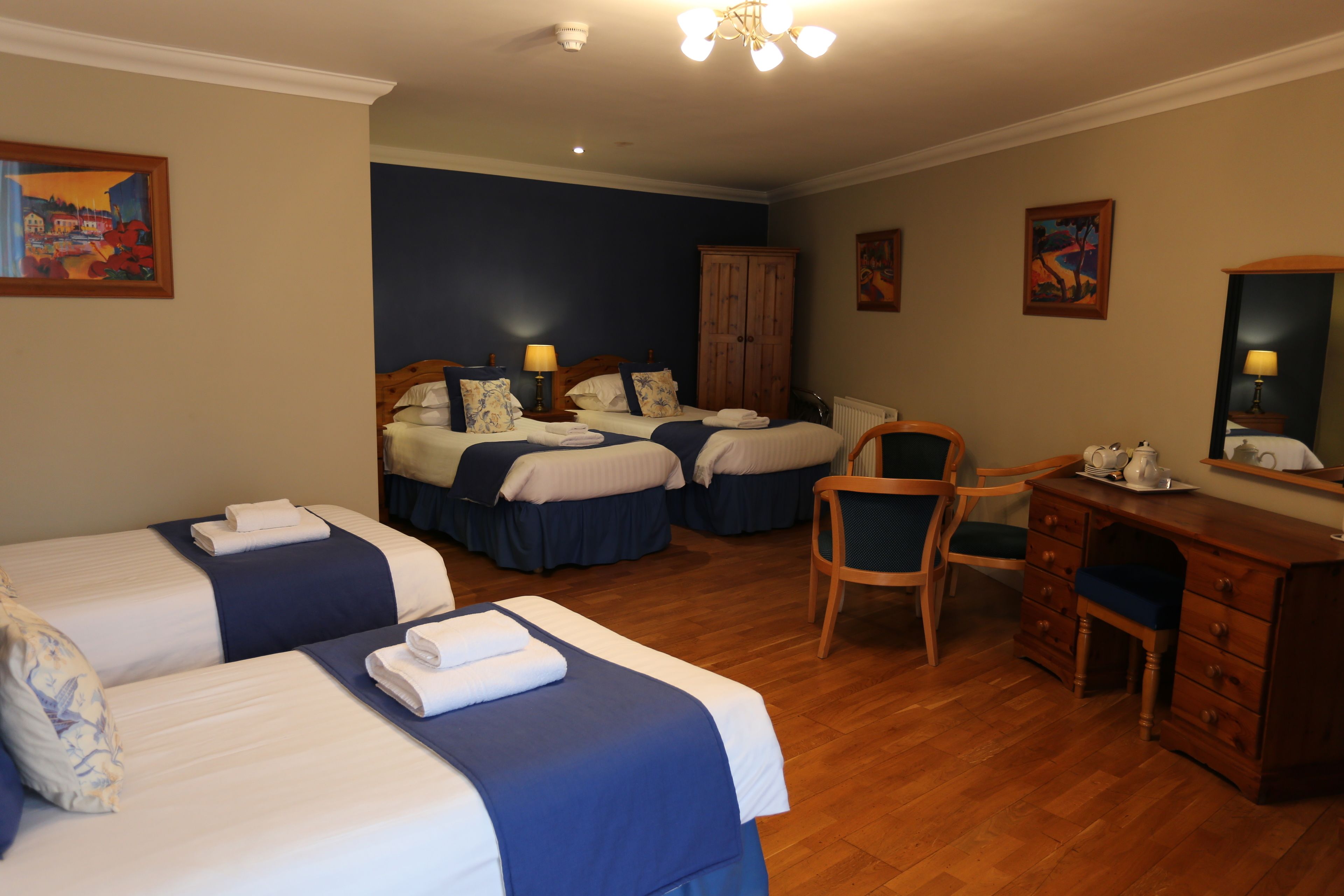 Ein Hotelzimmer mit zwei Betten, einem Holztisch, einem Stuhl und einem Schrank.