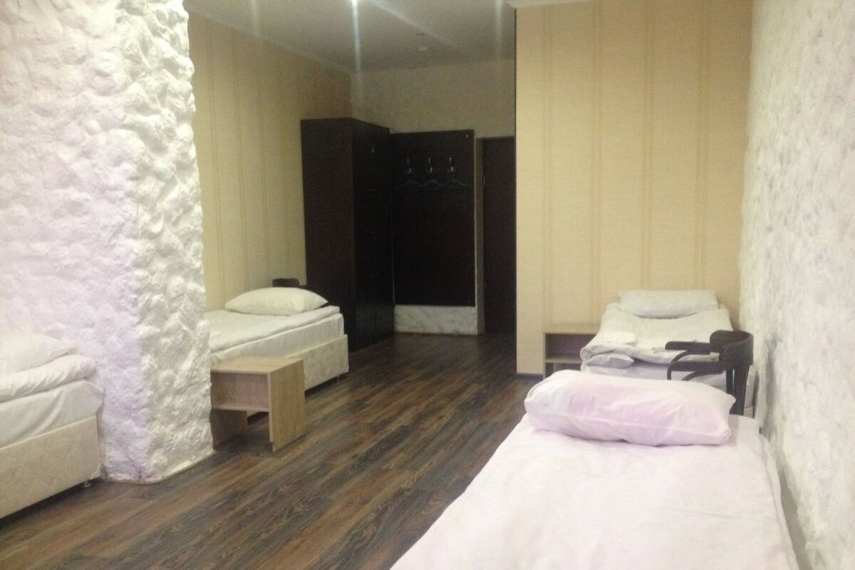 Hotellihuone, jossa on kaksi sänkyä, puulattia ja kivestä tehty korosteseinä.