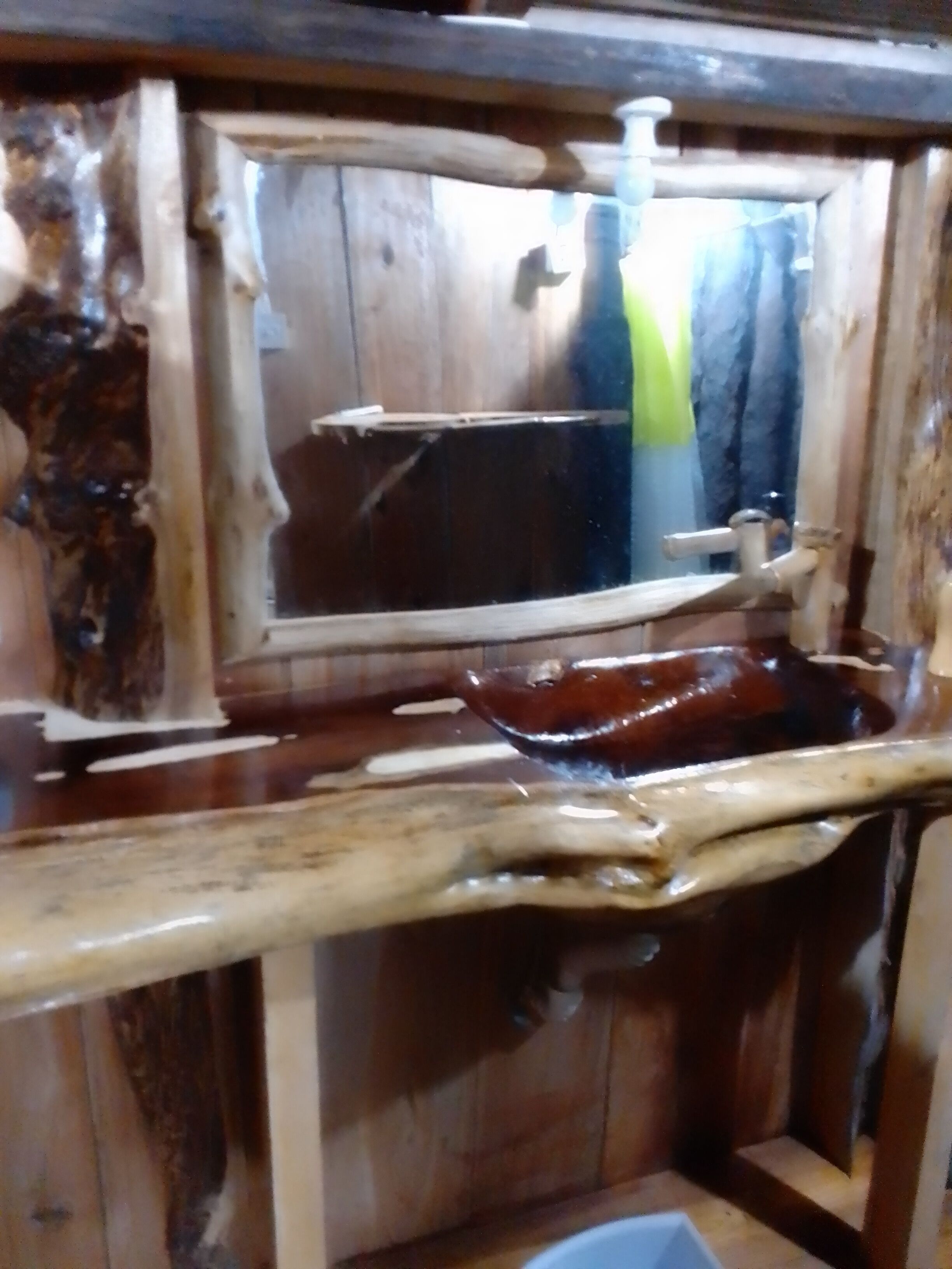 Un interior rústico de madera con un banco, un espejo y una ventana.
