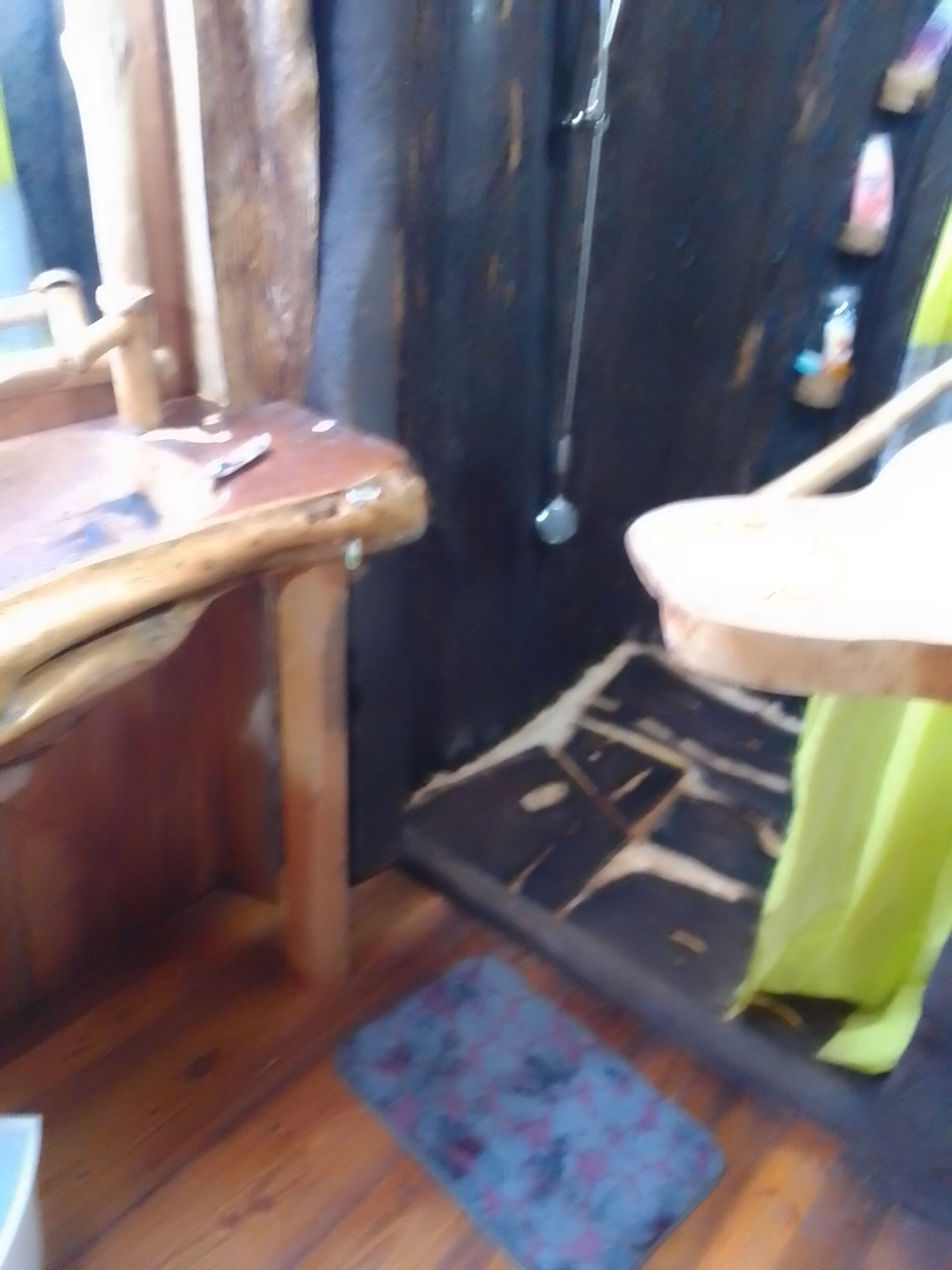 A room with a wooden table, a chair, a patterned rug, and a door with a curtain.