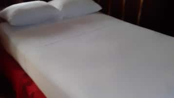 Ein Bett mit weißer Bettwäsche und einem roten Bettvorhang.