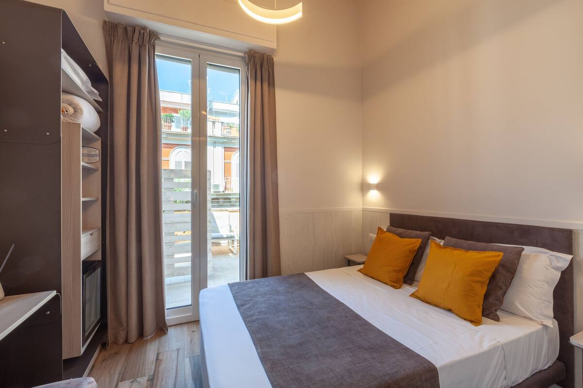 A hotel room with a bed, a wardrobe, and a sliding glass door to the balcony.