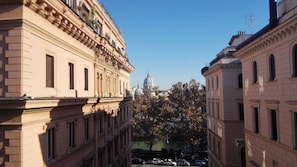 A street view with classical architecture, including buildings with ornate facades and a prominent dome structure in the background. - Residenza Cavallini (Rome)