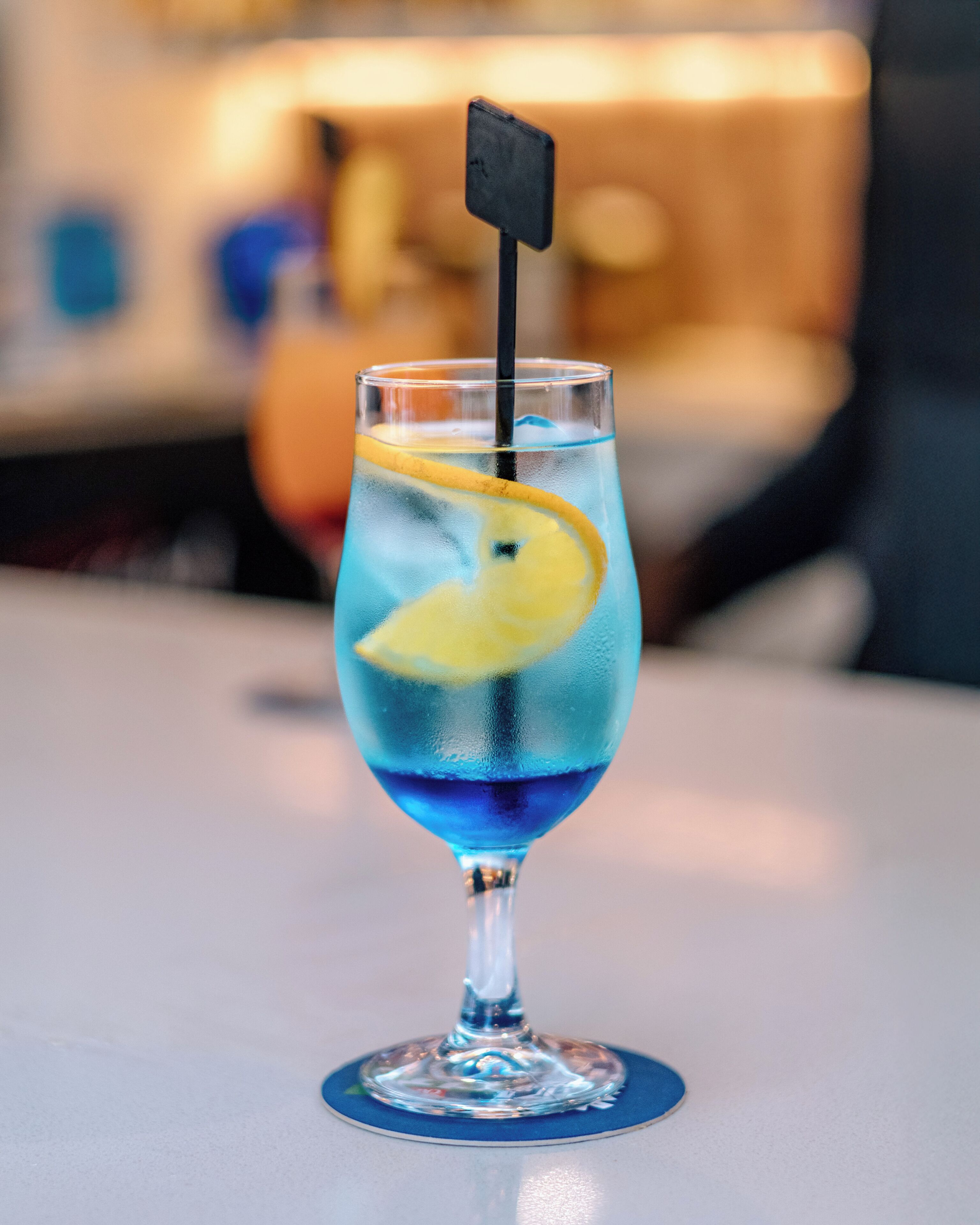 A cocktail glass with a lemon slice garnish on a bar counter.