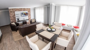 A modern living room with a fireplace, a TV mounted on a brick wall, and a dining area with a table and chairs.