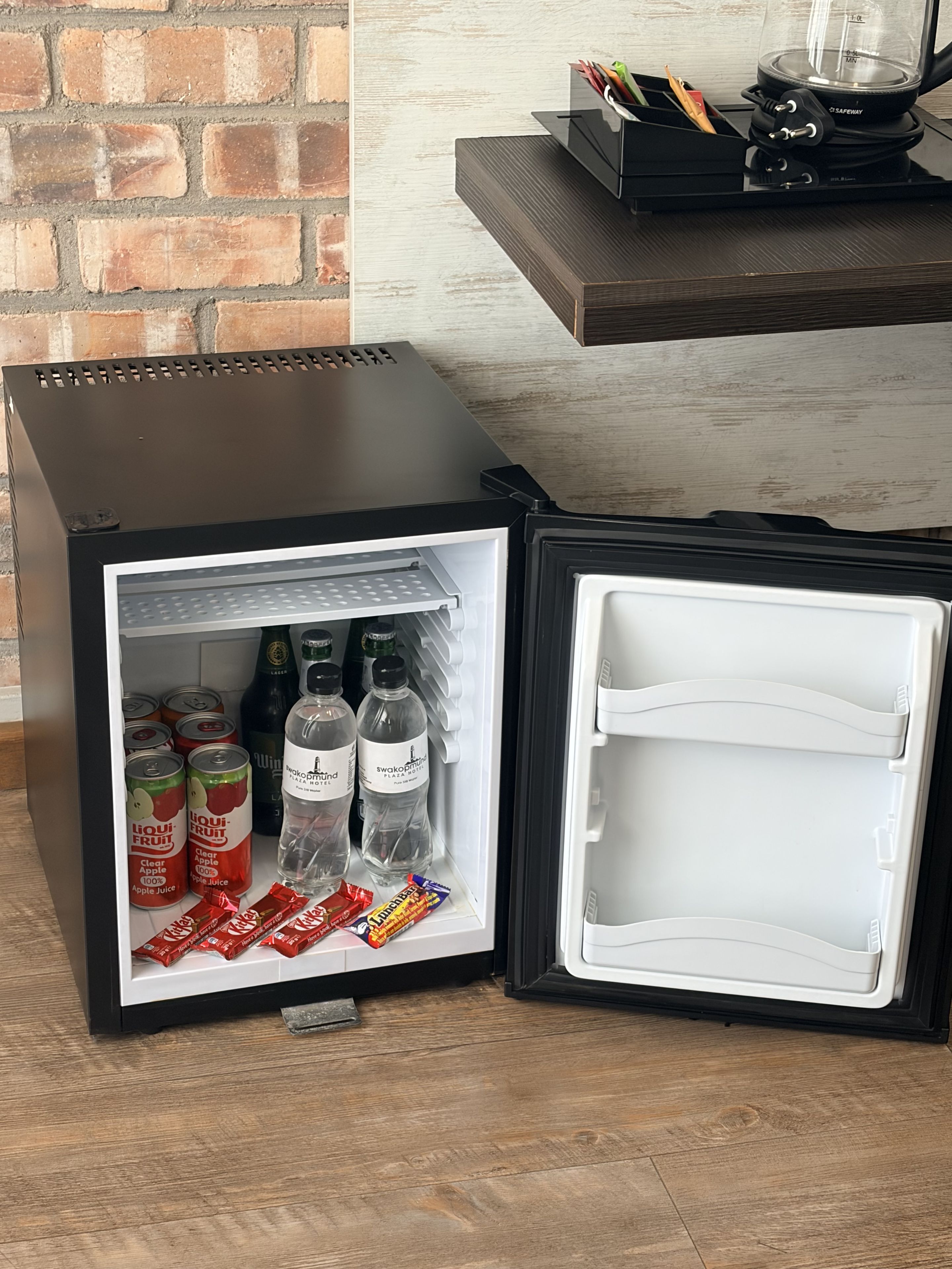 A compact refrigerator with a freezer compartment, containing beverages and snacks.