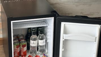 A compact refrigerator with a freezer compartment, containing beverages and snacks.