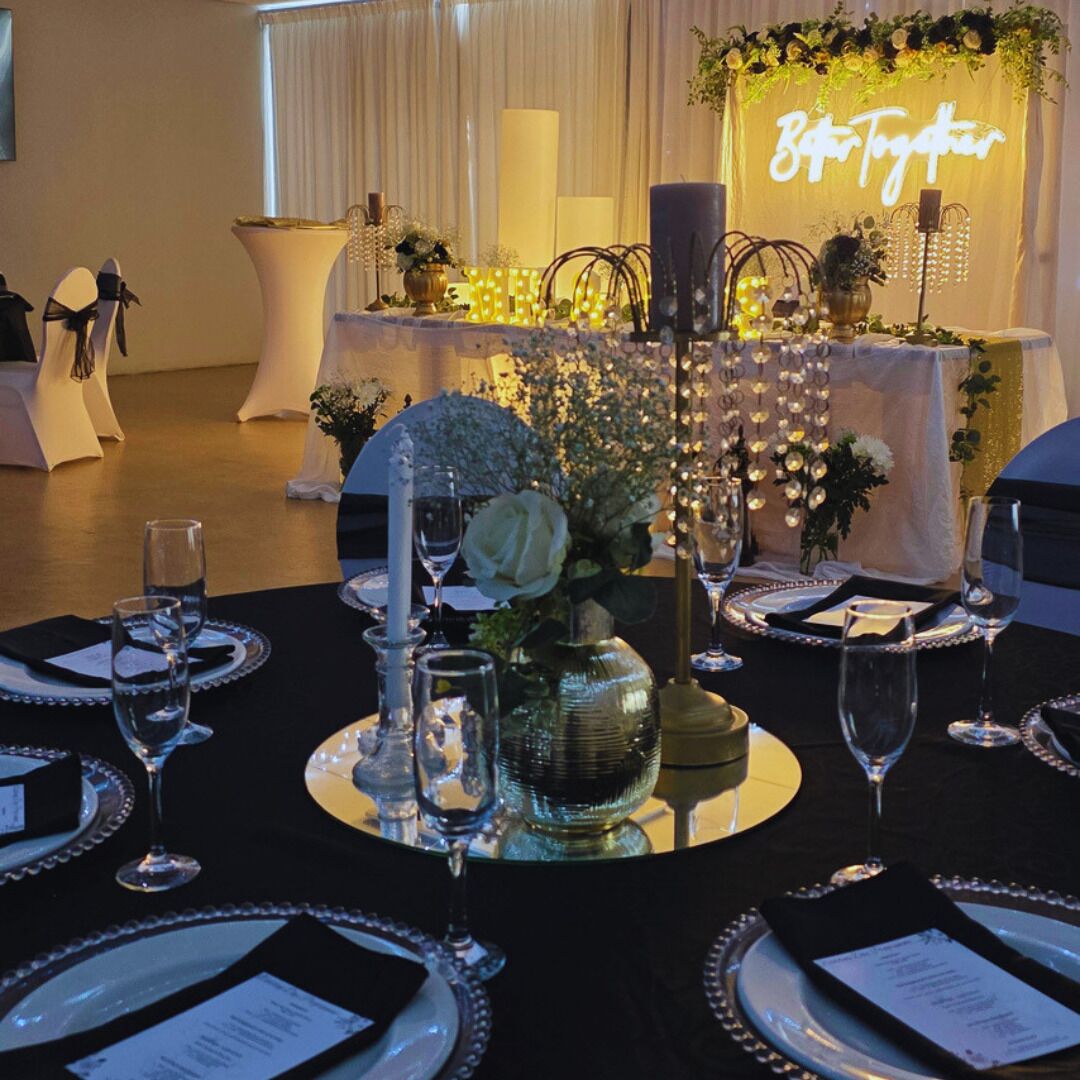 Mesa dispuesta para un evento formal, con un letrero de neón que dice 'Together' al fondo.