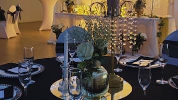 Mesa dispuesta para un evento formal, con un letrero de neón que dice 'Together' al fondo.