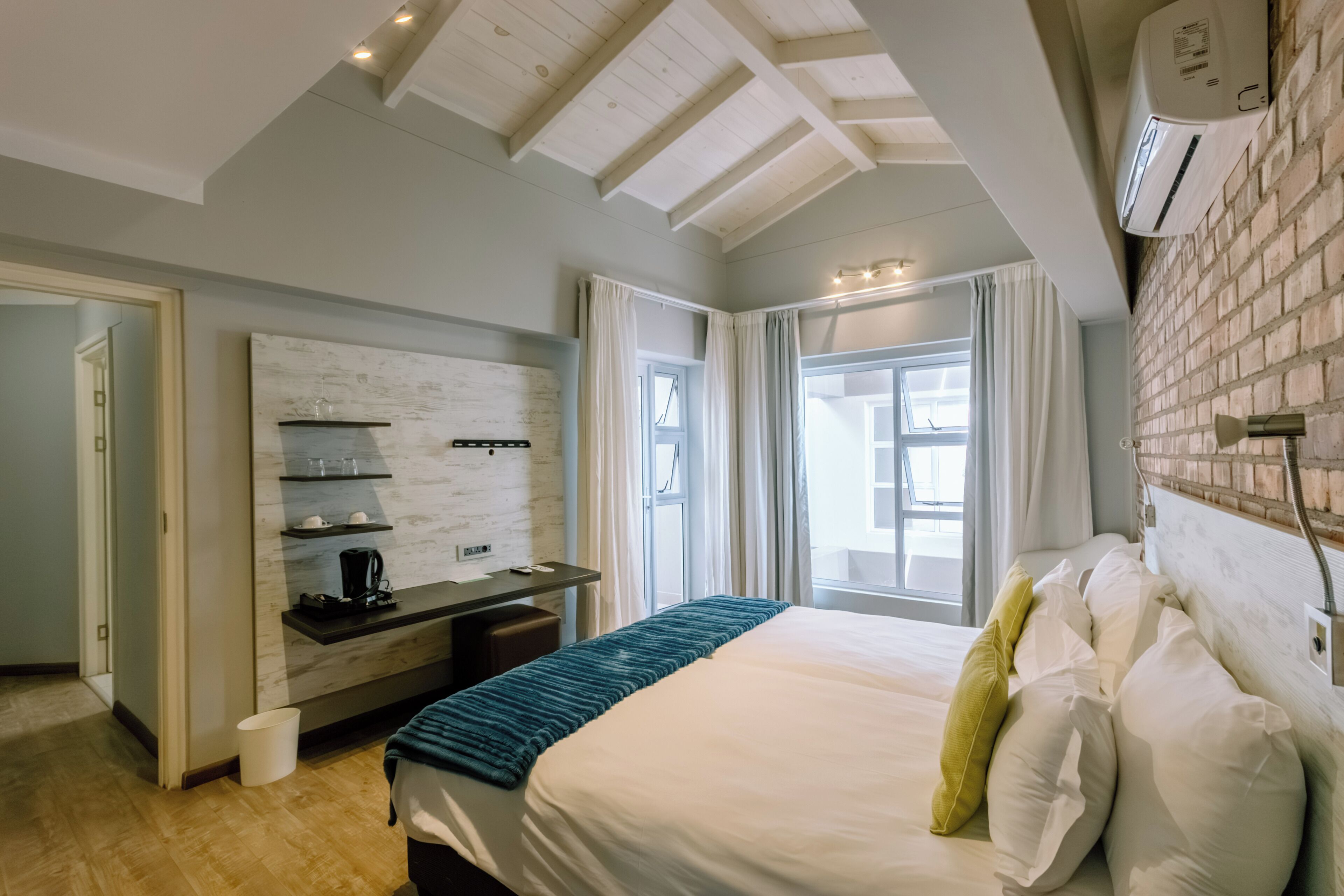 A hotel room with a bed, a desk, a coffee machine, and a window with curtains.