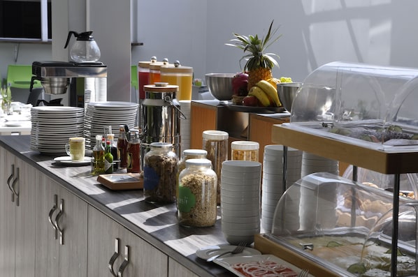 Montaje de bufé con diferentes alimentos, salsas y utensilios para servir.