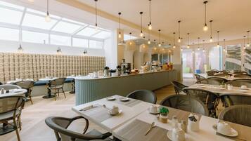 A modern dining area with high ceilings, pendant lighting, and a central bar area.