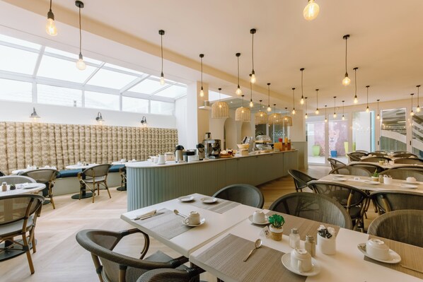 A modern dining area with high ceilings, pendant lighting, and a central bar area.