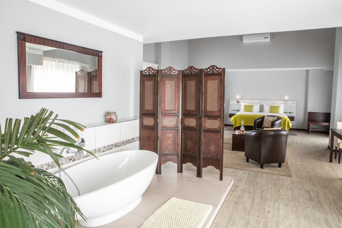 A modern bathroom with a freestanding bathtub, a large mirror, and a wooden partition.